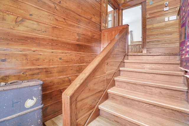 stairway featuring wooden walls