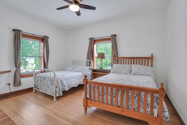 bedroom with ceiling fan, light hardwood / wood-style floors, and multiple windows