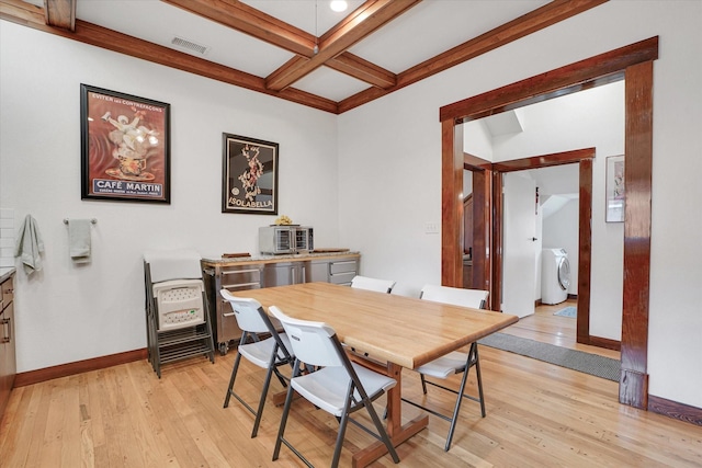 dining room featuring beam ceiling, washer / clothes dryer, light hardwood / wood-style flooring, and coffered ceiling