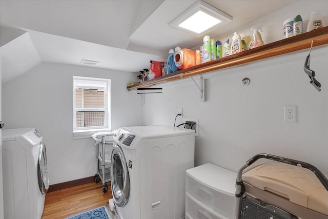 laundry room with washing machine and dryer and light wood-type flooring