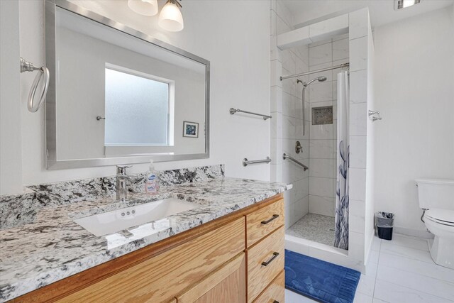 bathroom featuring a shower with shower curtain, tile patterned floors, vanity, and toilet