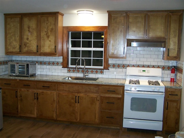 kitchen featuring decorative backsplash, dark hardwood / wood-style floors, white gas range, and sink