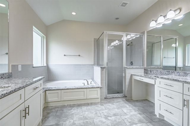 bathroom with independent shower and bath, lofted ceiling, tile floors, and large vanity