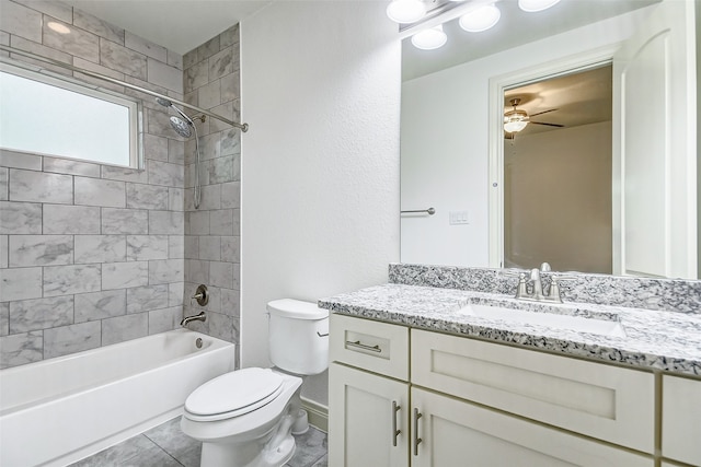 full bathroom with tile flooring, vanity with extensive cabinet space, tiled shower / bath combo, ceiling fan, and toilet