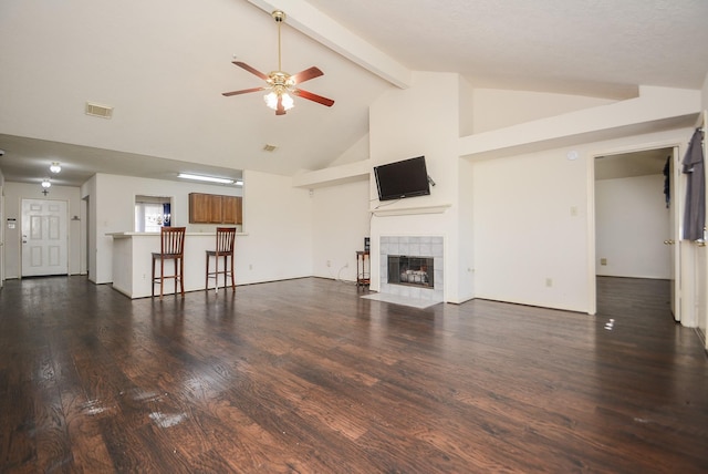 unfurnished living room featuring visible vents, beamed ceiling, a fireplace, wood finished floors, and a ceiling fan