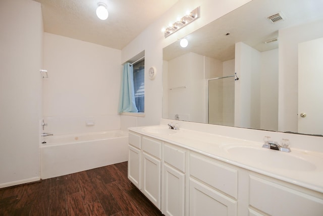 bathroom with a sink, visible vents, wood finished floors, and a bath