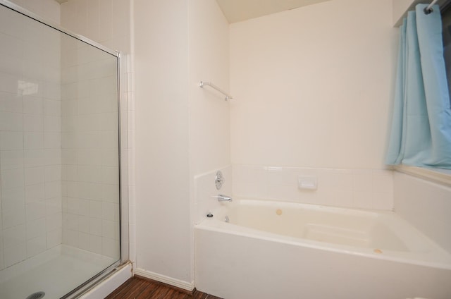 full bathroom with a bath, a shower stall, baseboards, and wood finished floors