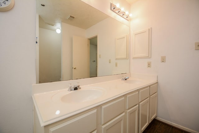 full bathroom featuring double vanity, visible vents, baseboards, and a sink