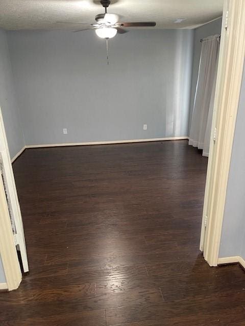 spare room with dark wood finished floors, baseboards, and ceiling fan