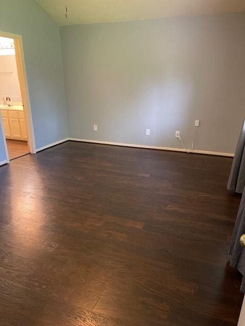 empty room featuring baseboards and dark wood-style flooring