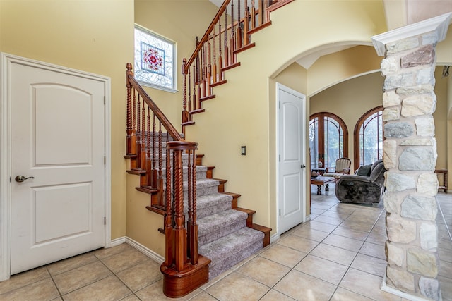 stairway with ornate columns, tile patterned floors, and a healthy amount of sunlight