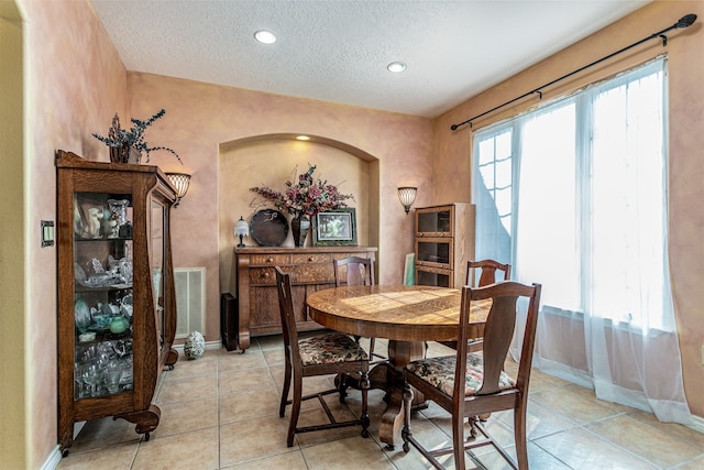 tiled dining space with a textured ceiling