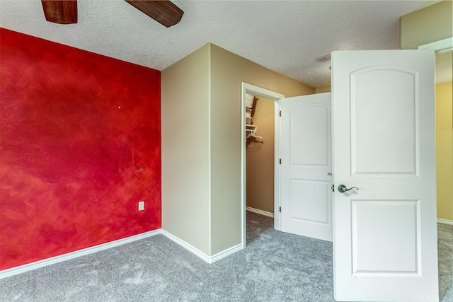 unfurnished bedroom featuring a spacious closet, carpet, ceiling fan, and a closet