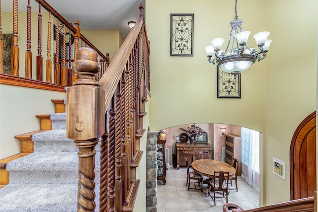 stairway with a high ceiling, a chandelier, and tile patterned flooring