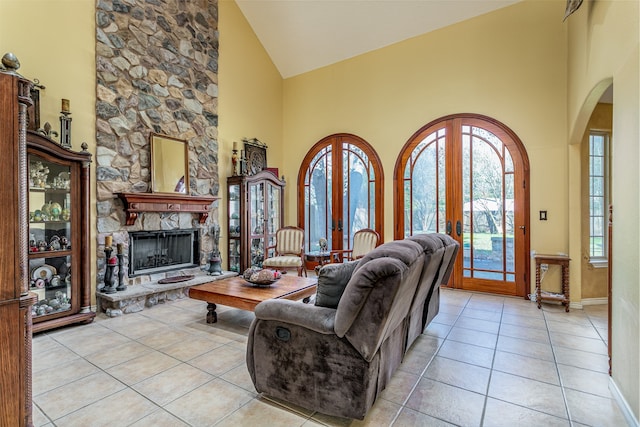 tiled living room with a fireplace, a healthy amount of sunlight, french doors, and high vaulted ceiling