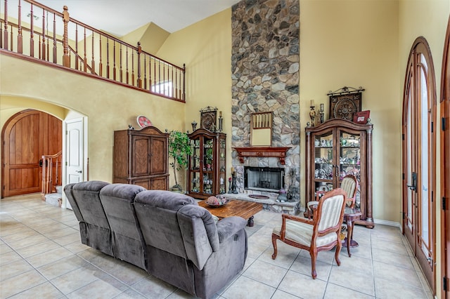 living room featuring a fireplace, light tile patterned floors, and a towering ceiling