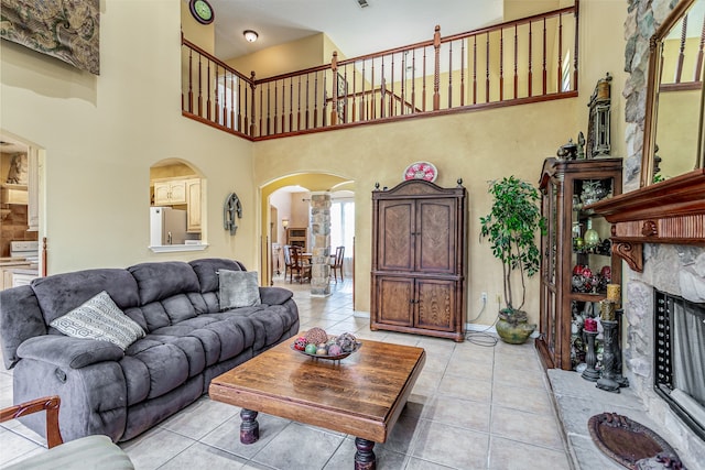 tiled living room with a stone fireplace and a towering ceiling