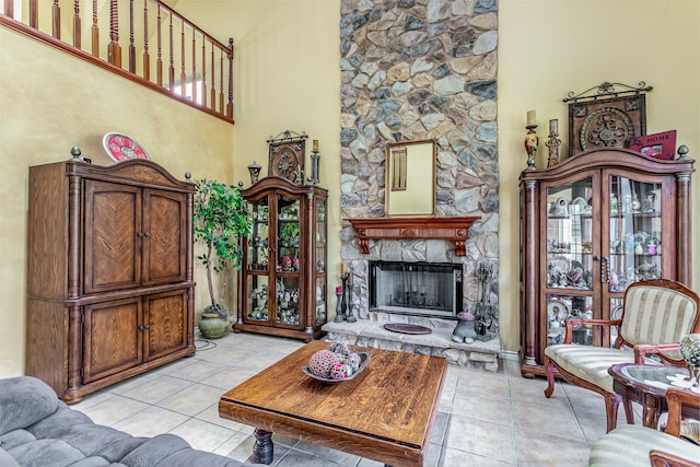 living room with a fireplace, light tile patterned floors, and a high ceiling