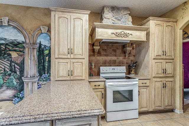 kitchen with light tile patterned flooring, a textured ceiling, white electric stove, light stone counters, and light brown cabinetry