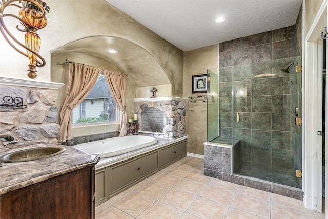 bathroom featuring independent shower and bath, dual sinks, tile patterned floors, and a textured ceiling