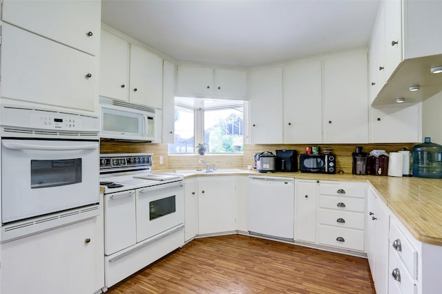 kitchen with white appliances, light hardwood / wood-style flooring, white cabinetry, and sink