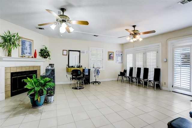 tiled living room featuring a fireplace and ceiling fan