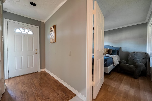 foyer entrance with ornamental molding, hardwood / wood-style floors, and a textured ceiling