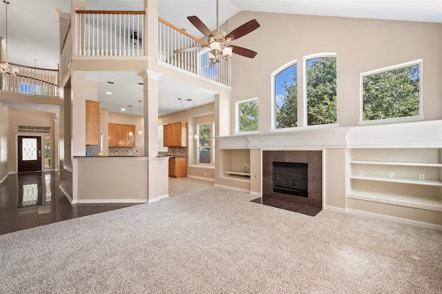 unfurnished living room with high vaulted ceiling, ceiling fan, light colored carpet, and a fireplace