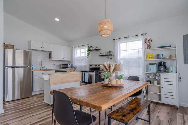 dining space featuring light hardwood / wood-style floors, sink, and vaulted ceiling