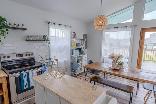 kitchen featuring hanging light fixtures, decorative backsplash, a wealth of natural light, and stainless steel range with electric stovetop