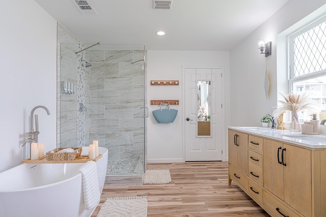 bathroom featuring hardwood / wood-style flooring, vanity, and shower with separate bathtub