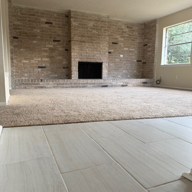 unfurnished living room featuring carpet flooring and brick wall