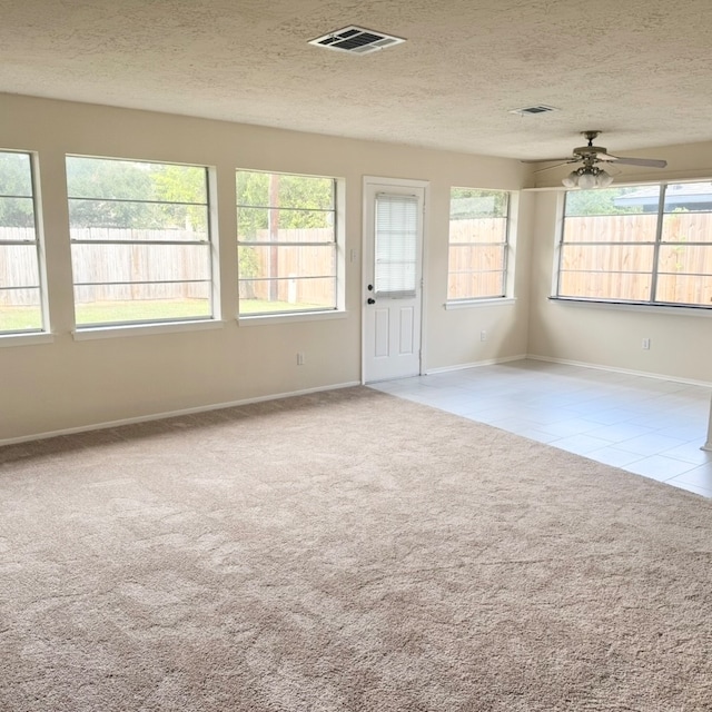 carpeted empty room with ceiling fan and a textured ceiling