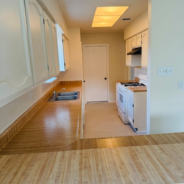 kitchen featuring white cabinets, light hardwood / wood-style floors, gas range gas stove, and sink