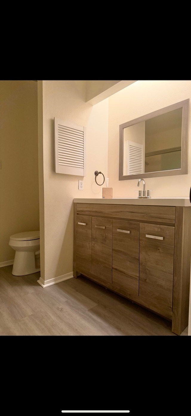 bathroom featuring toilet, vanity, and hardwood / wood-style flooring