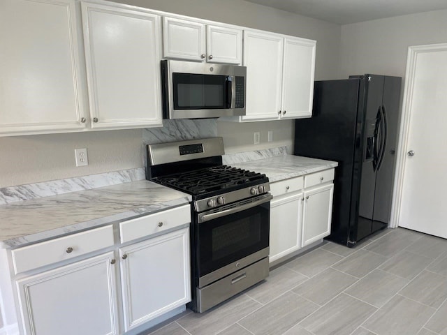 kitchen featuring light stone countertops, appliances with stainless steel finishes, and white cabinetry