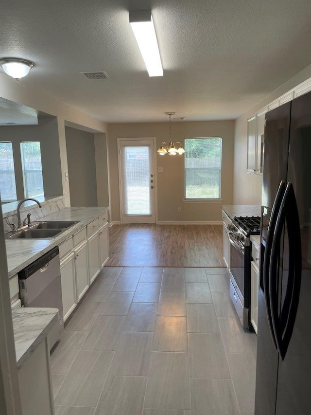 kitchen with white cabinetry, sink, light stone countertops, and appliances with stainless steel finishes