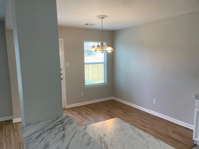 unfurnished dining area featuring hardwood / wood-style floors and a notable chandelier