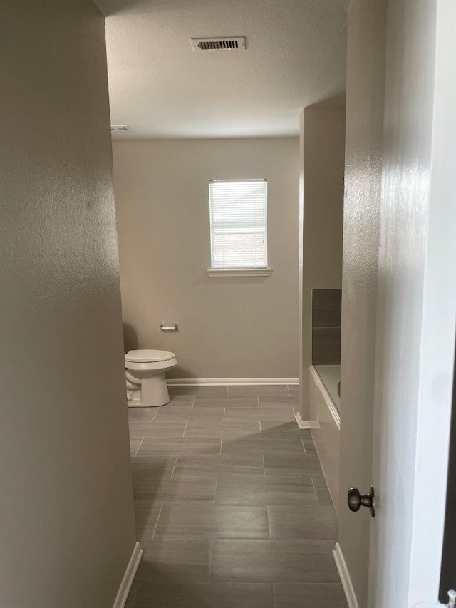 bathroom featuring a washtub and toilet