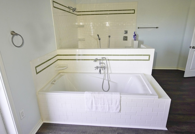 bathroom with a relaxing tiled tub and hardwood / wood-style flooring