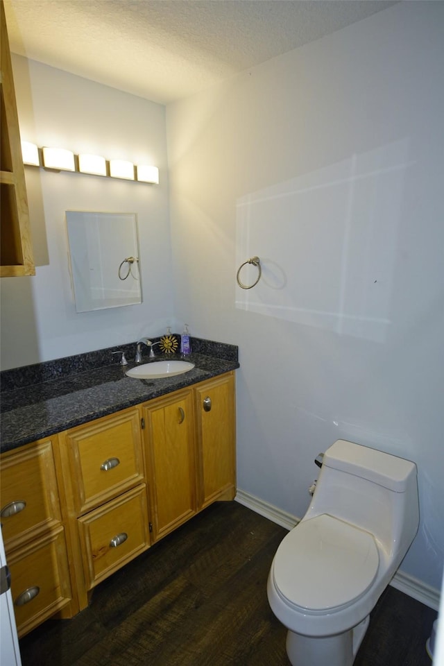 bathroom featuring hardwood / wood-style flooring, vanity, toilet, and a textured ceiling