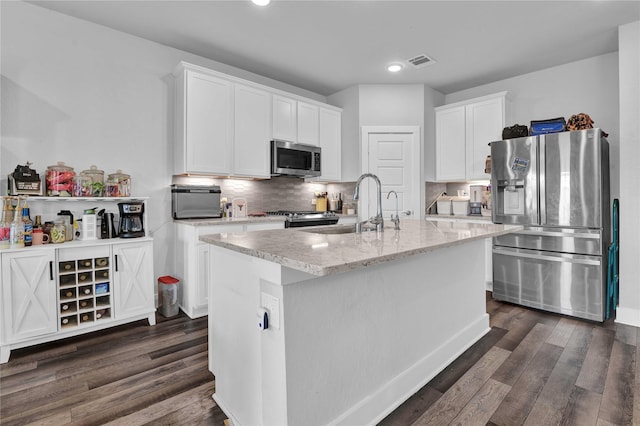 kitchen featuring sink, appliances with stainless steel finishes, tasteful backsplash, an island with sink, and white cabinets