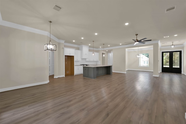 unfurnished living room featuring ceiling fan with notable chandelier, french doors, dark hardwood / wood-style floors, and crown molding