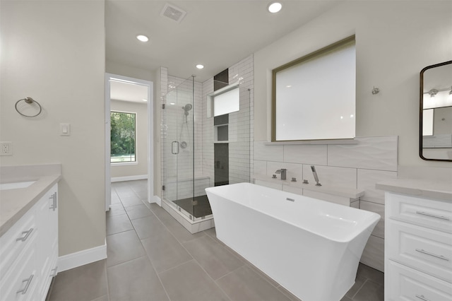 bathroom featuring independent shower and bath, vanity, tile patterned floors, and tile walls