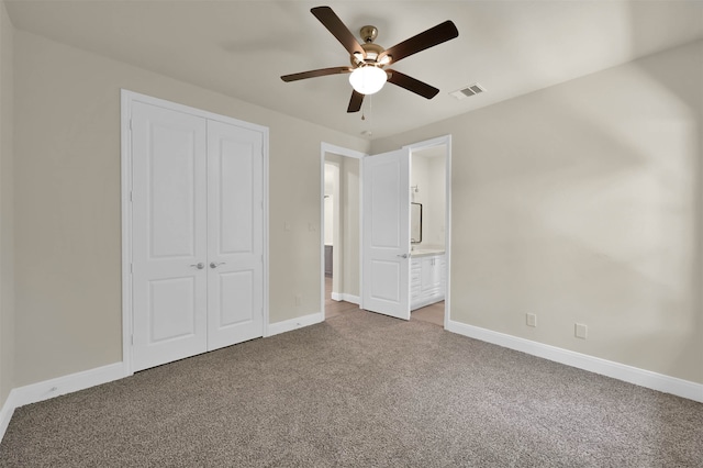 unfurnished bedroom with a closet, ensuite bathroom, carpet floors, and ceiling fan