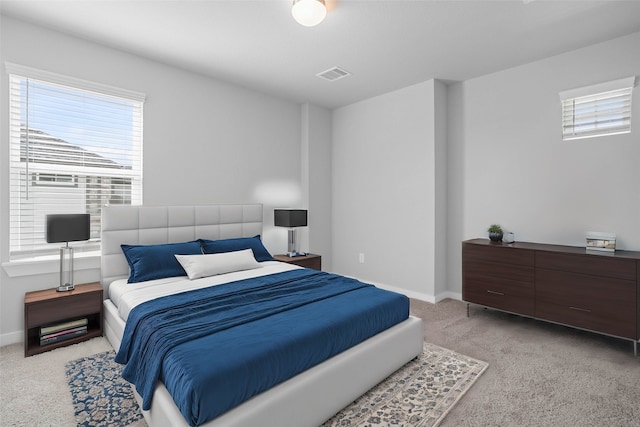 bedroom featuring light carpet and multiple windows