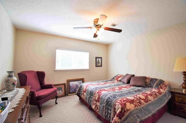 carpeted bedroom with ceiling fan and a textured ceiling