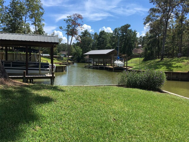 view of dock with a lawn and a water view