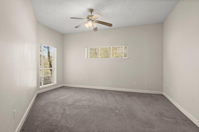 carpeted empty room with a ceiling fan and baseboards