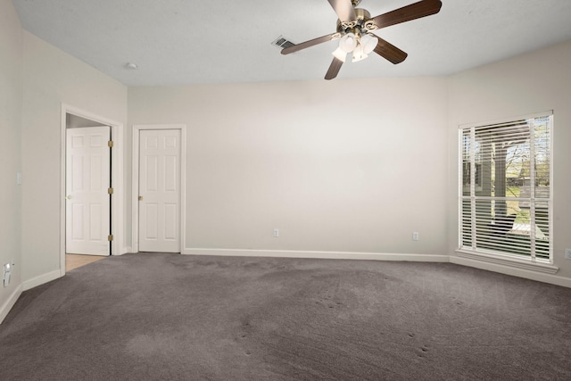 carpeted empty room with baseboards, visible vents, and a ceiling fan